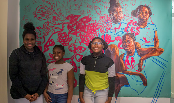 Three Children stand in front of Trustman Exhibit piece